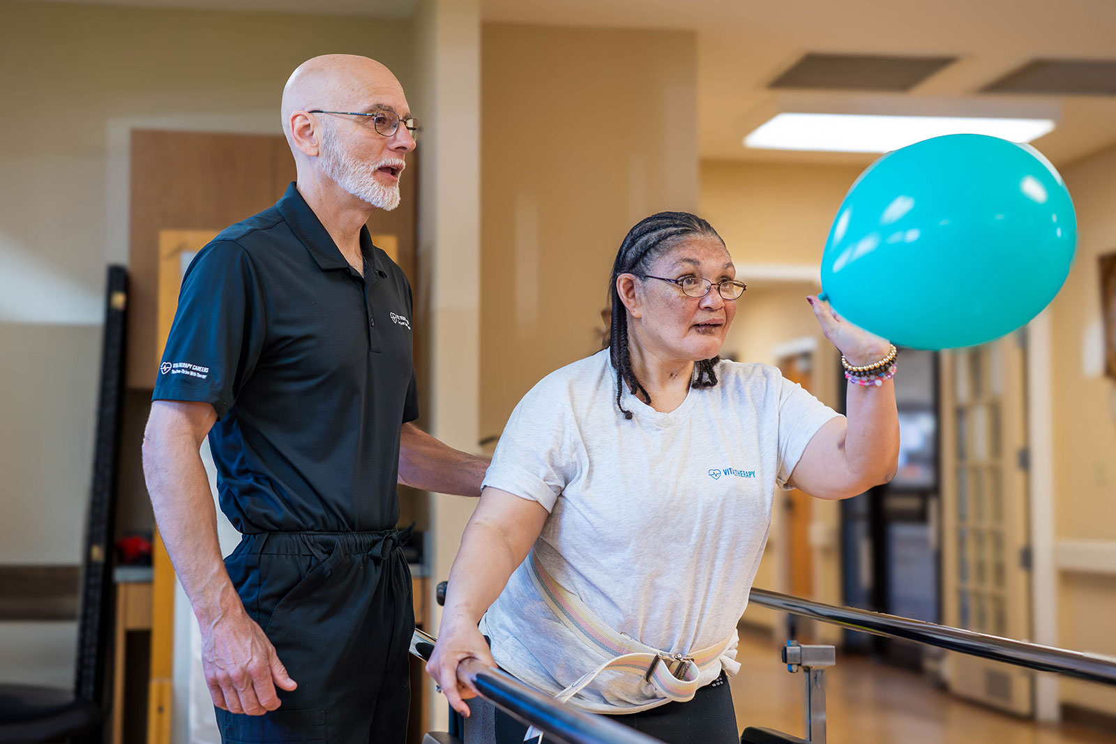 Patient practicing balance, supported by therapist, holding balloon.